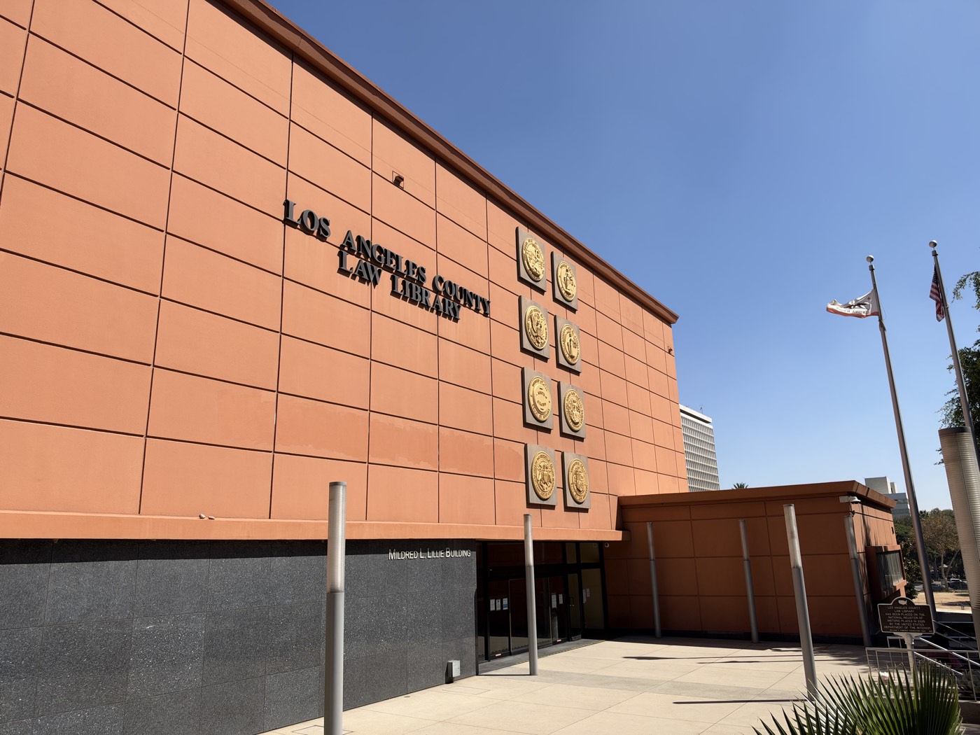 The Los Angeles County Law Library in the Mildred L. Lillie Building, with eight gold court seals on its terracotta facade and the California and United States flags